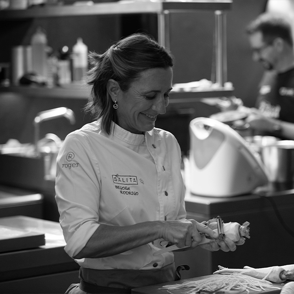 Begoña Rodrigo preparando ingredientes en una cocina profesional, en una fotografía en blanco y negro.