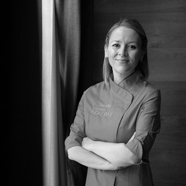 Teresa-Gutiérrez-posa-con-chaqueta-de-chef-del-Restaurante-Azafrán,-de-brazos-cruzados,-en-un-retrato-profesional.